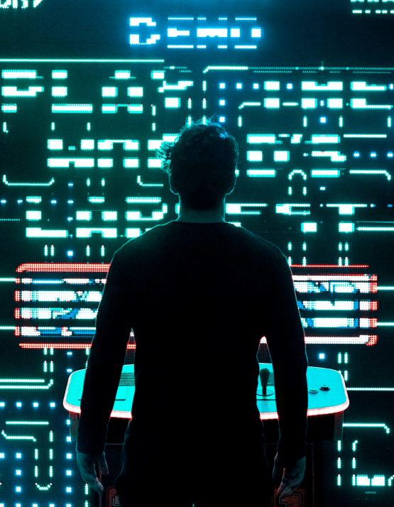 A person standing in front of a neon arcade screen